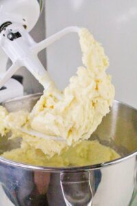 A mixing bowl with thick, creamy batter on a stand mixers paddle attachment.