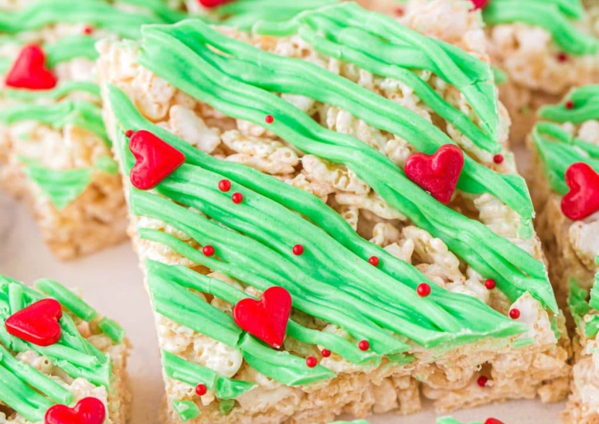 Rice Krispies treat bar topped with green frosting, red sprinkles, and red heart-shaped decorations.