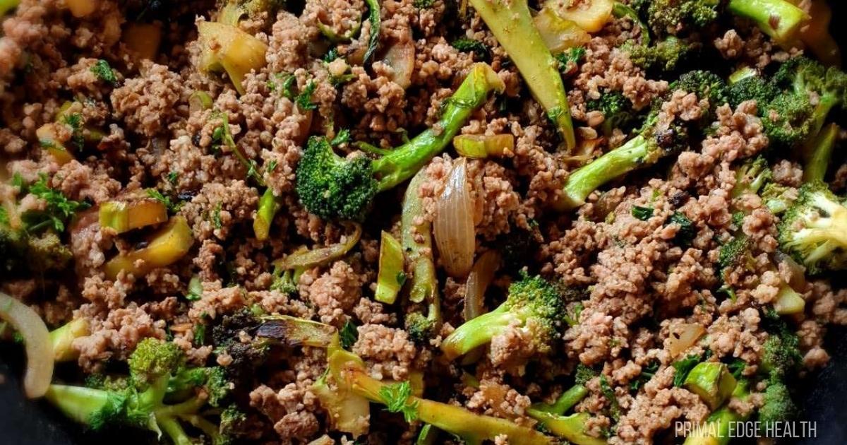 Cooked ground beef mixed with broccoli, onions, and celery in a skillet.