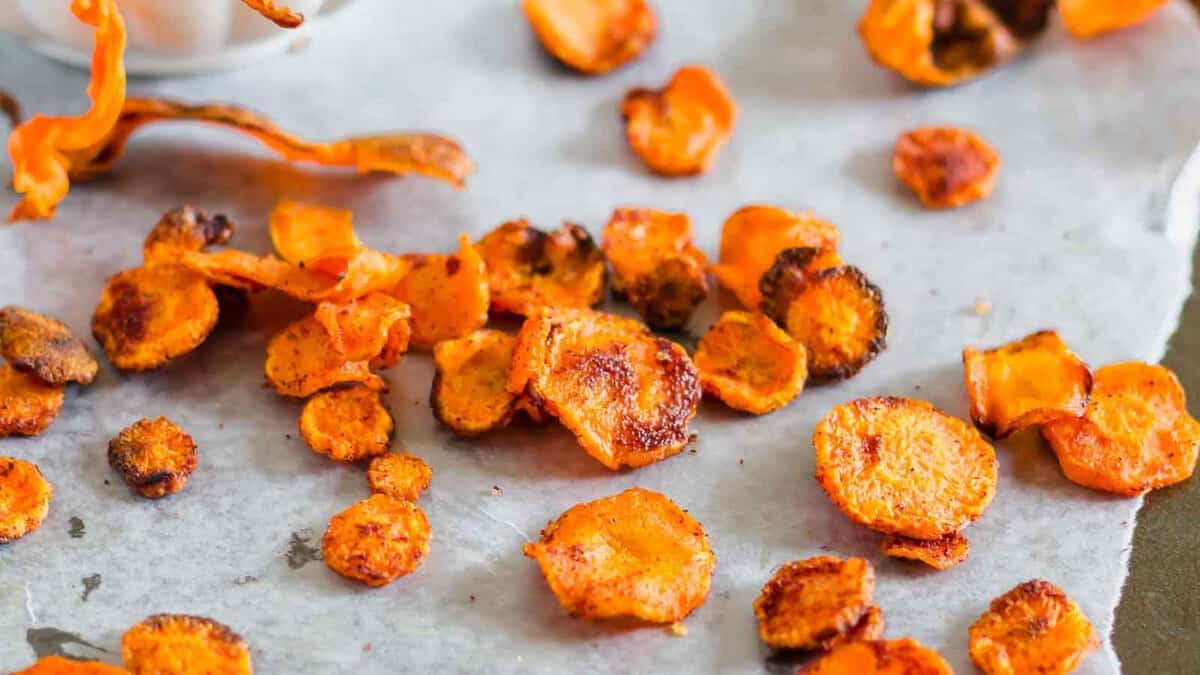 Baked carrot chips scattered on a sheet of parchment paper.