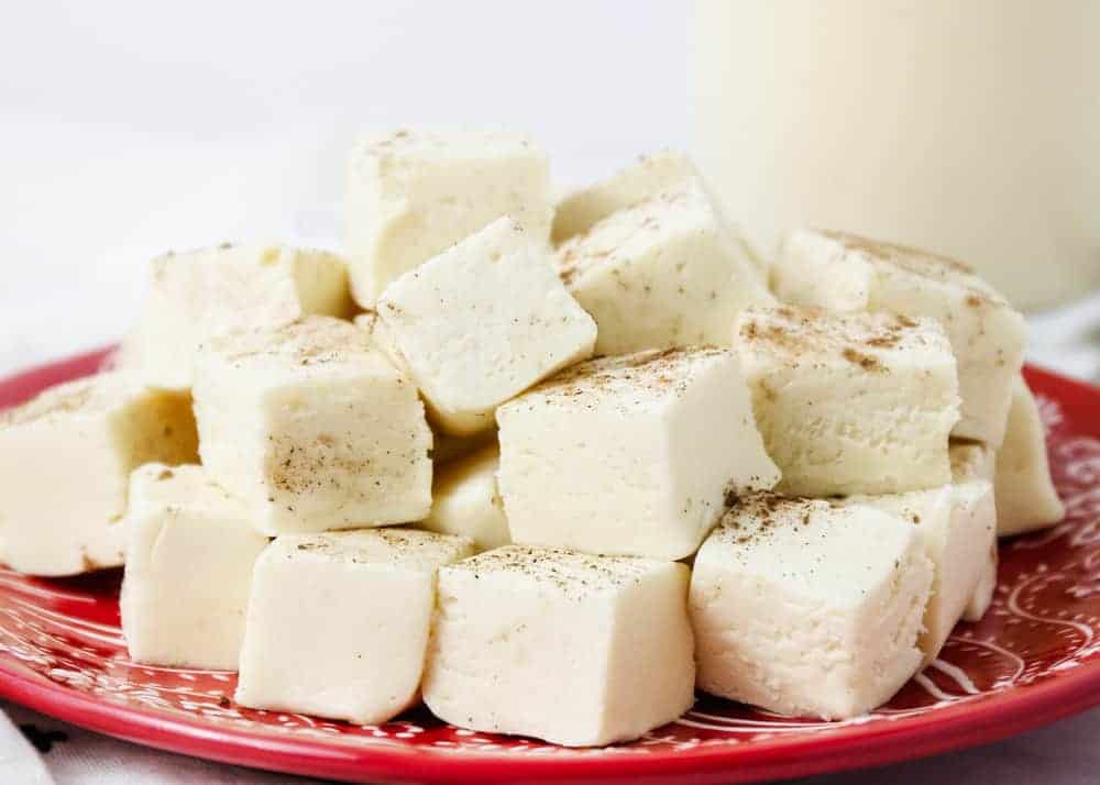 A red plate with stacked white fudge cubes, lightly sprinkled with ground nutmeg.
