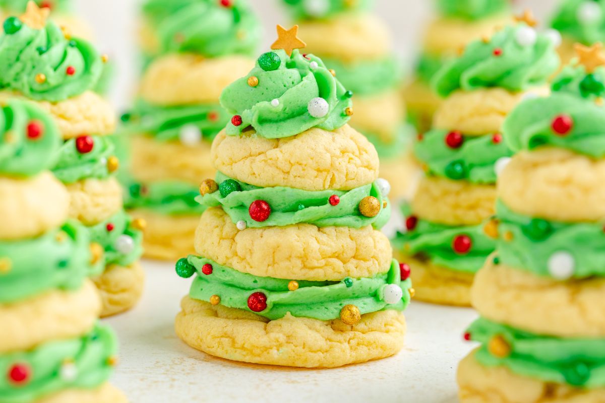 Stacked sugar cookies decorated with green frosting, sprinkles, and a star topper to resemble Christmas trees.