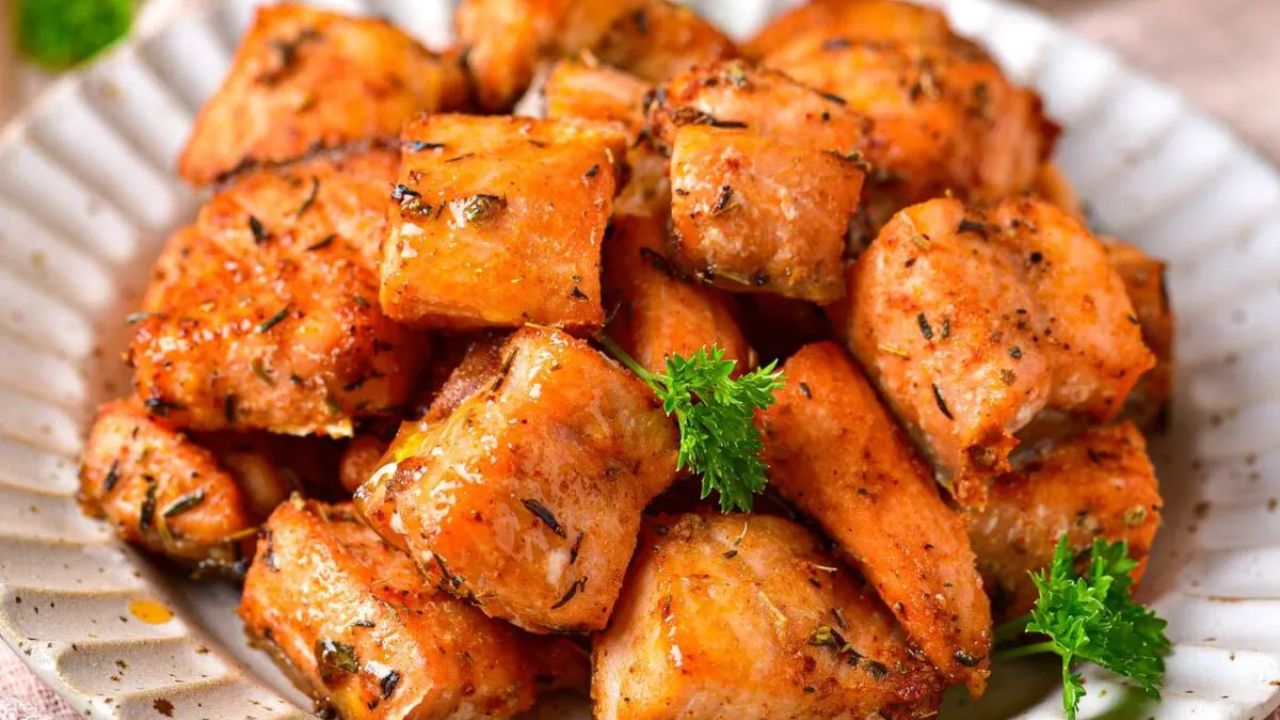 A plate of seasoned, cooked salmon cubes garnished with parsley.