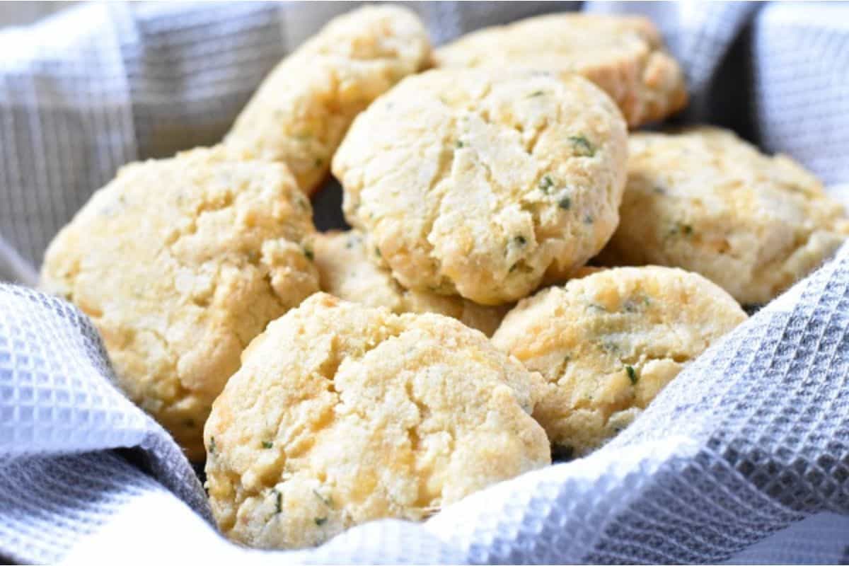 A close-up of several scone-like biscuits with a crumbly texture, resting on a gray and white checkered cloth.