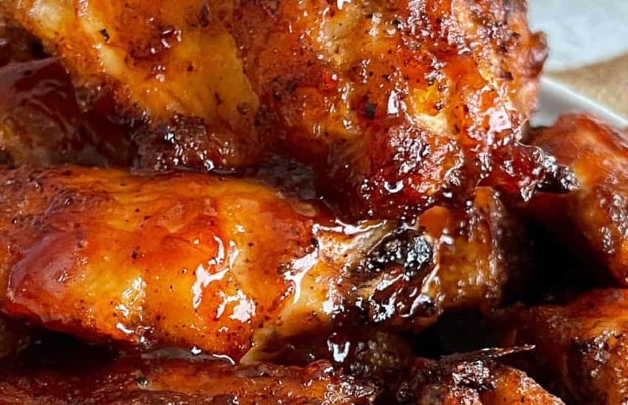 Close-up of glazed, grilled chicken wings with a shiny, caramelized surface and visible seasoning.