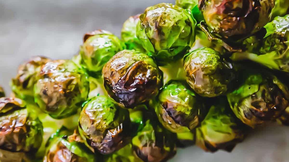 Close-up of roasted Brussels sprouts still attached to the stalk, showing browned and crispy outer leaves.