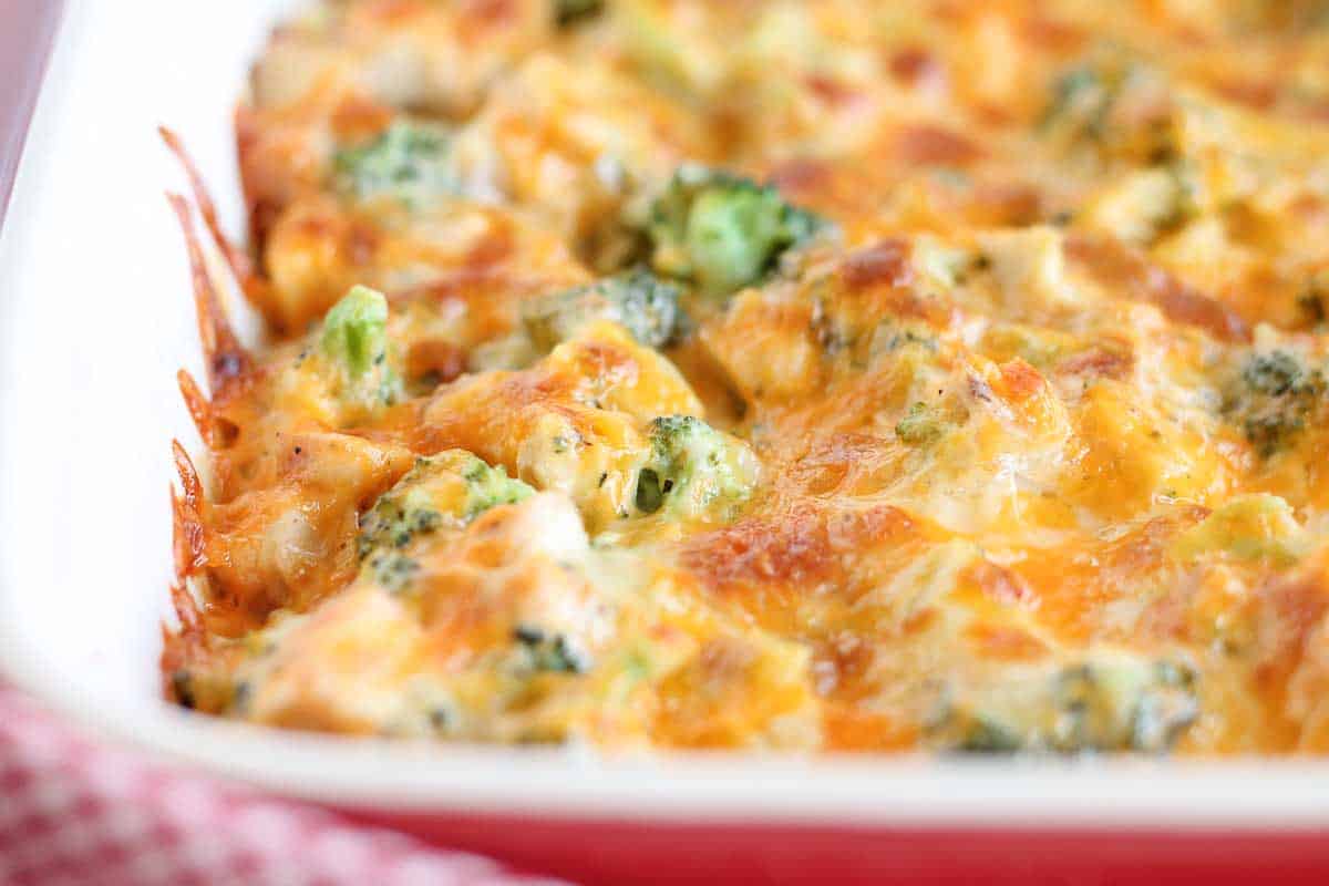 A baked broccoli and cheese casserole with a golden, bubbly cheese topping in a white dish.