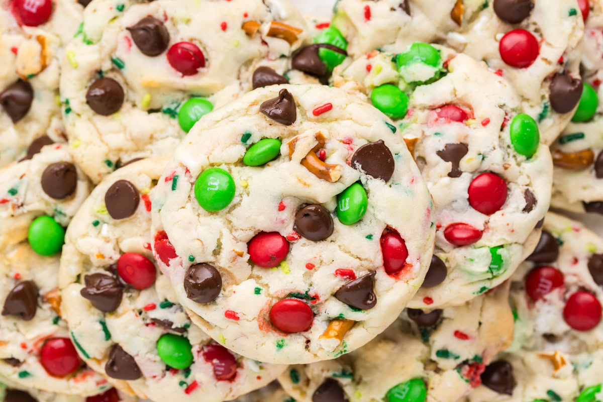 A pile of cookies topped with red and green candy-coated chocolates and chocolate chips.