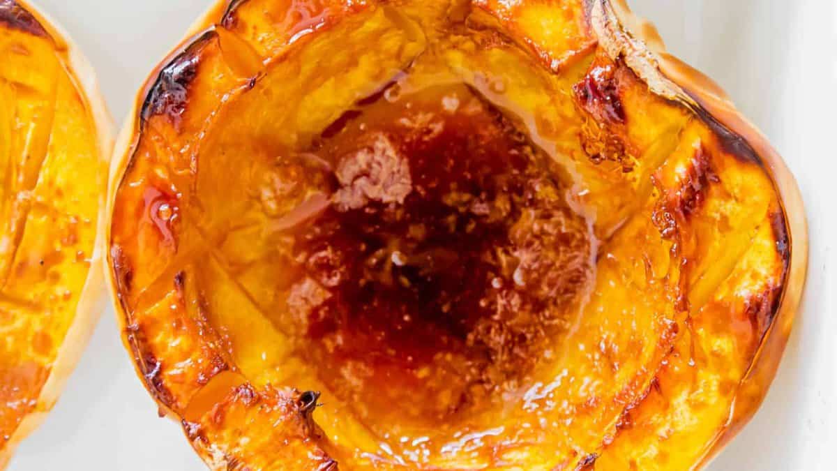 Close-up of a roasted acorn squash half with caramelized, browned center and edges, showing glossy texture and baked surface.