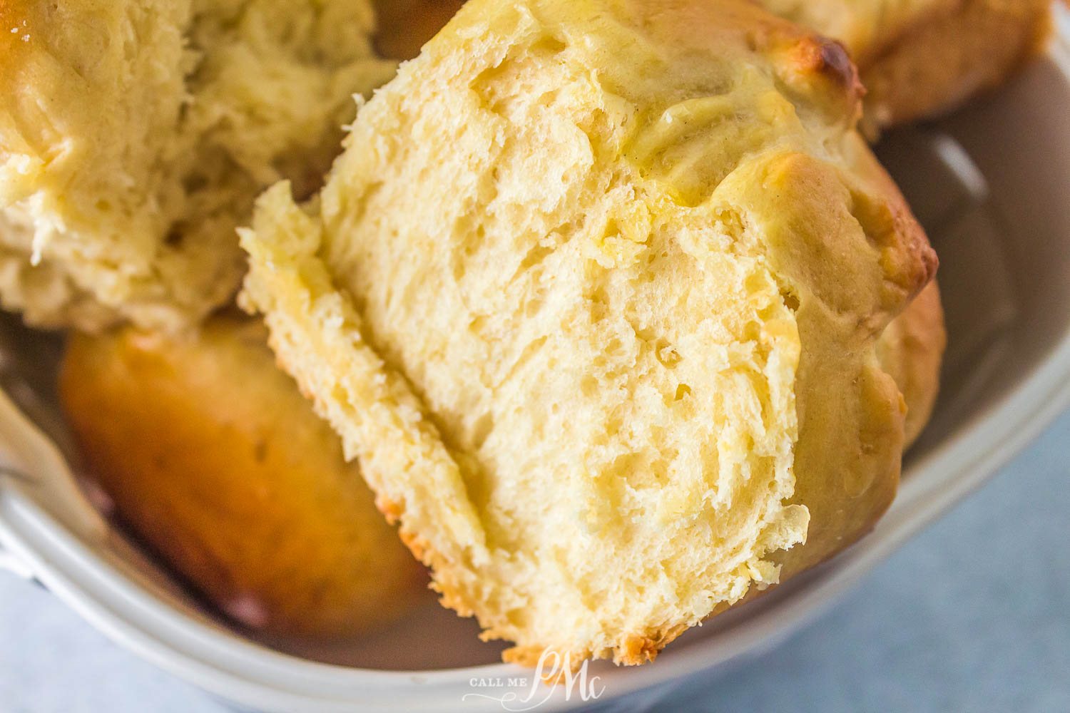 Close-up of a golden, freshly baked biscuit split open to show its soft, fluffy interior, placed in a white dish.