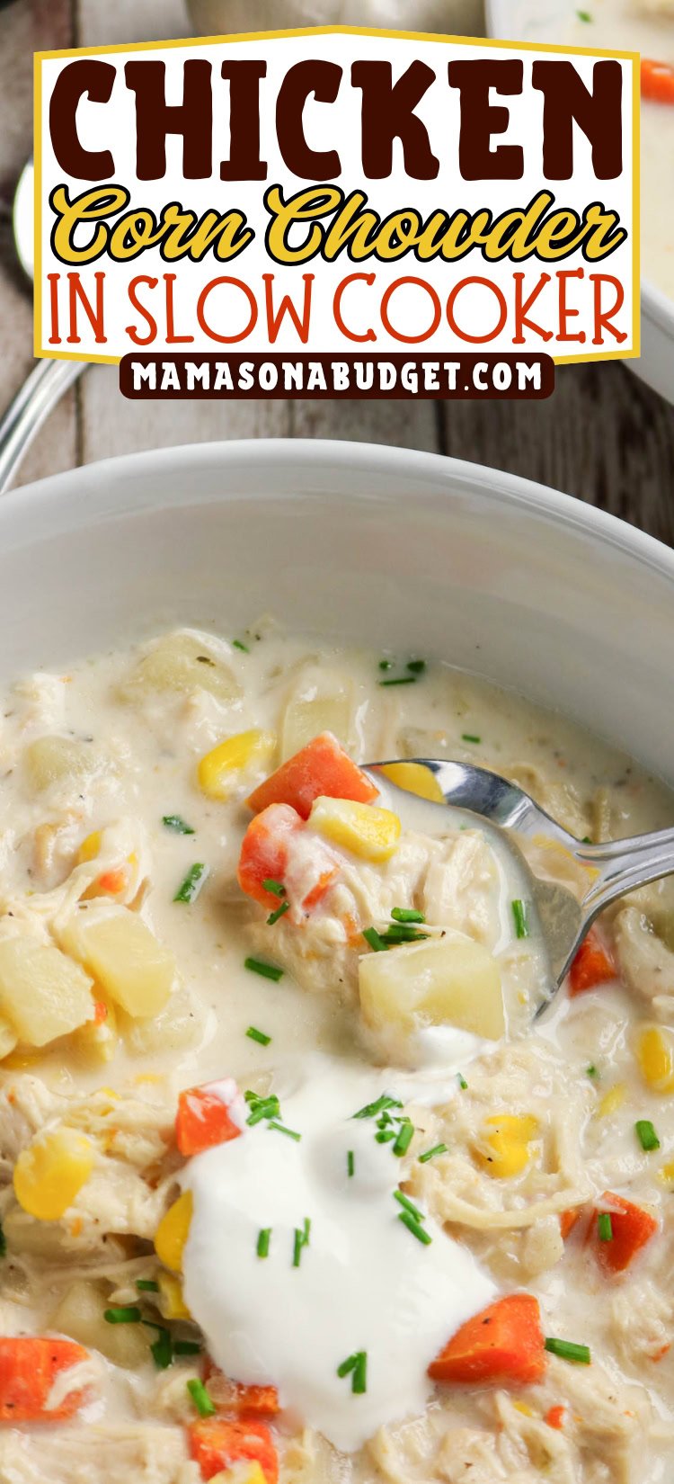 A bowl of chicken corn chowder topped with sour cream and chives, with chunks of chicken, corn, potatoes, and carrots visible; a spoon rests in the bowl.