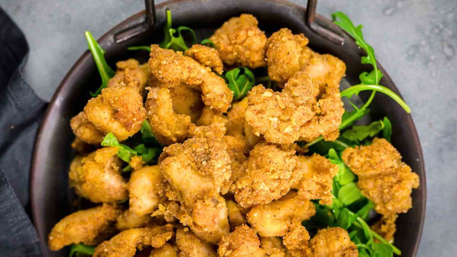 A bowl filled with pieces of golden-brown fried chicken served on a bed of fresh green arugula leaves.