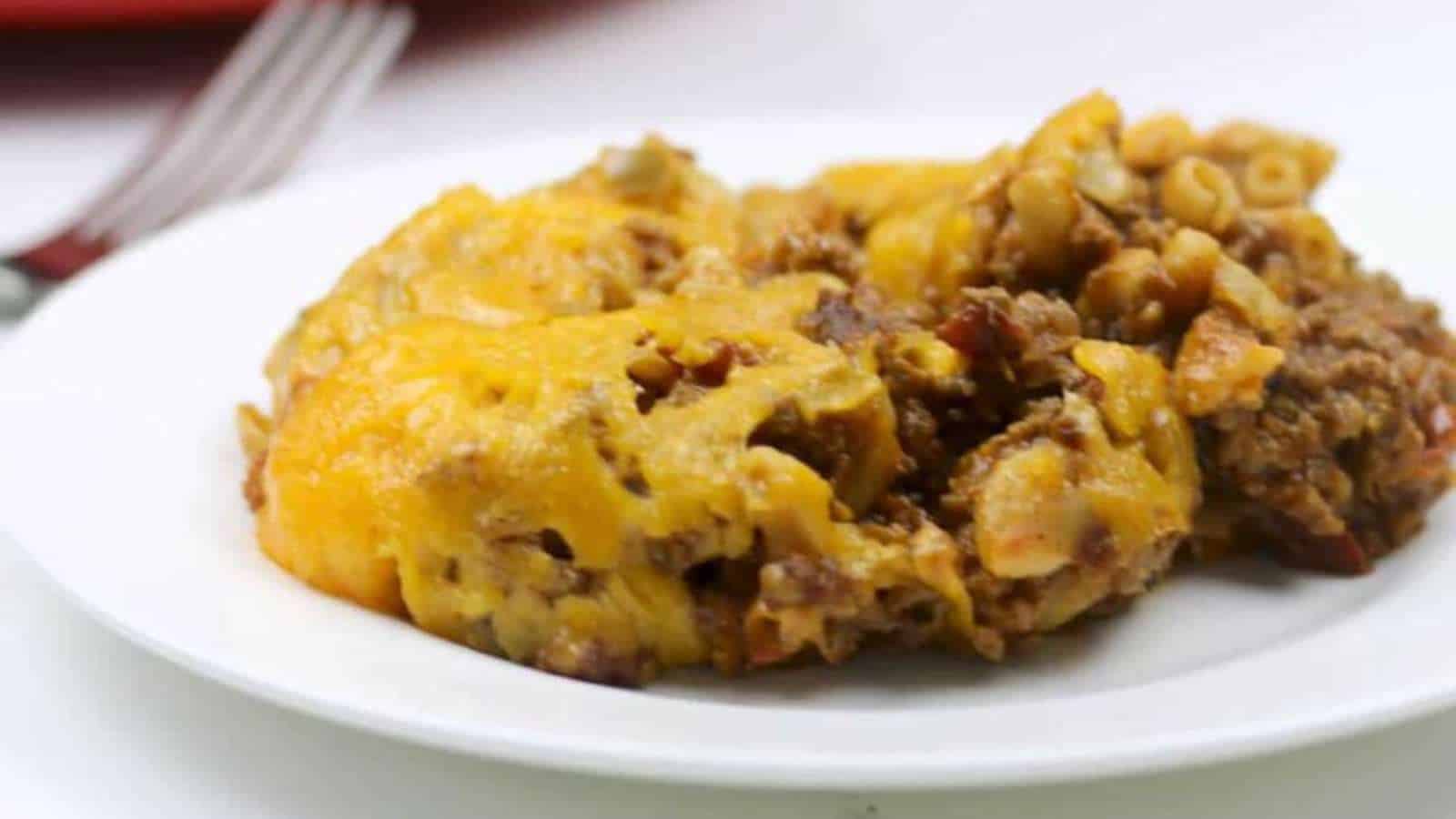 A serving of cheesy ground beef casserole with pasta on a white plate.