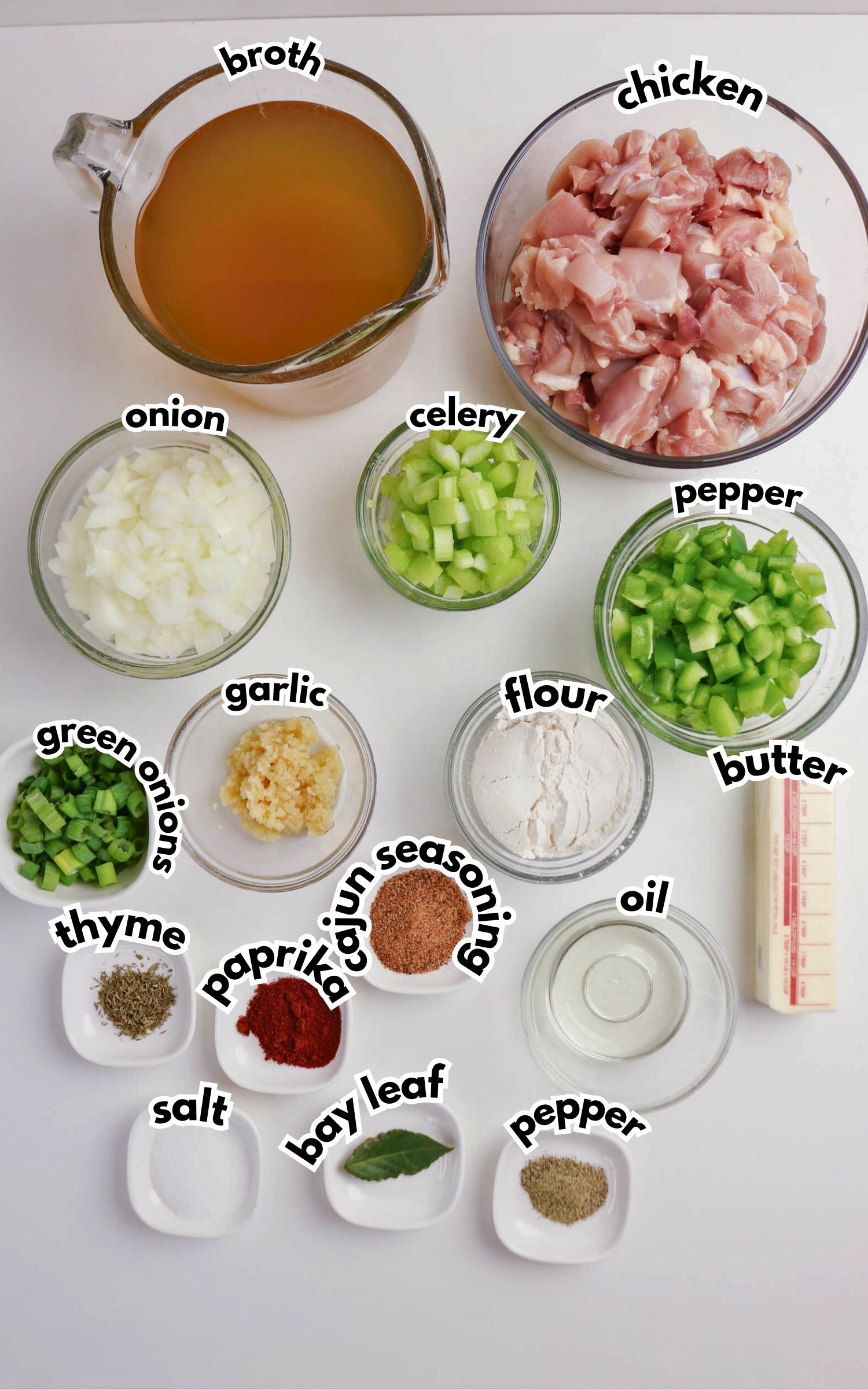Ingredients for a chicken dish are arranged in bowls and plates, including broth, chicken, onion, celery, green pepper, garlic, flour, butter, oil, herbs, and spices.