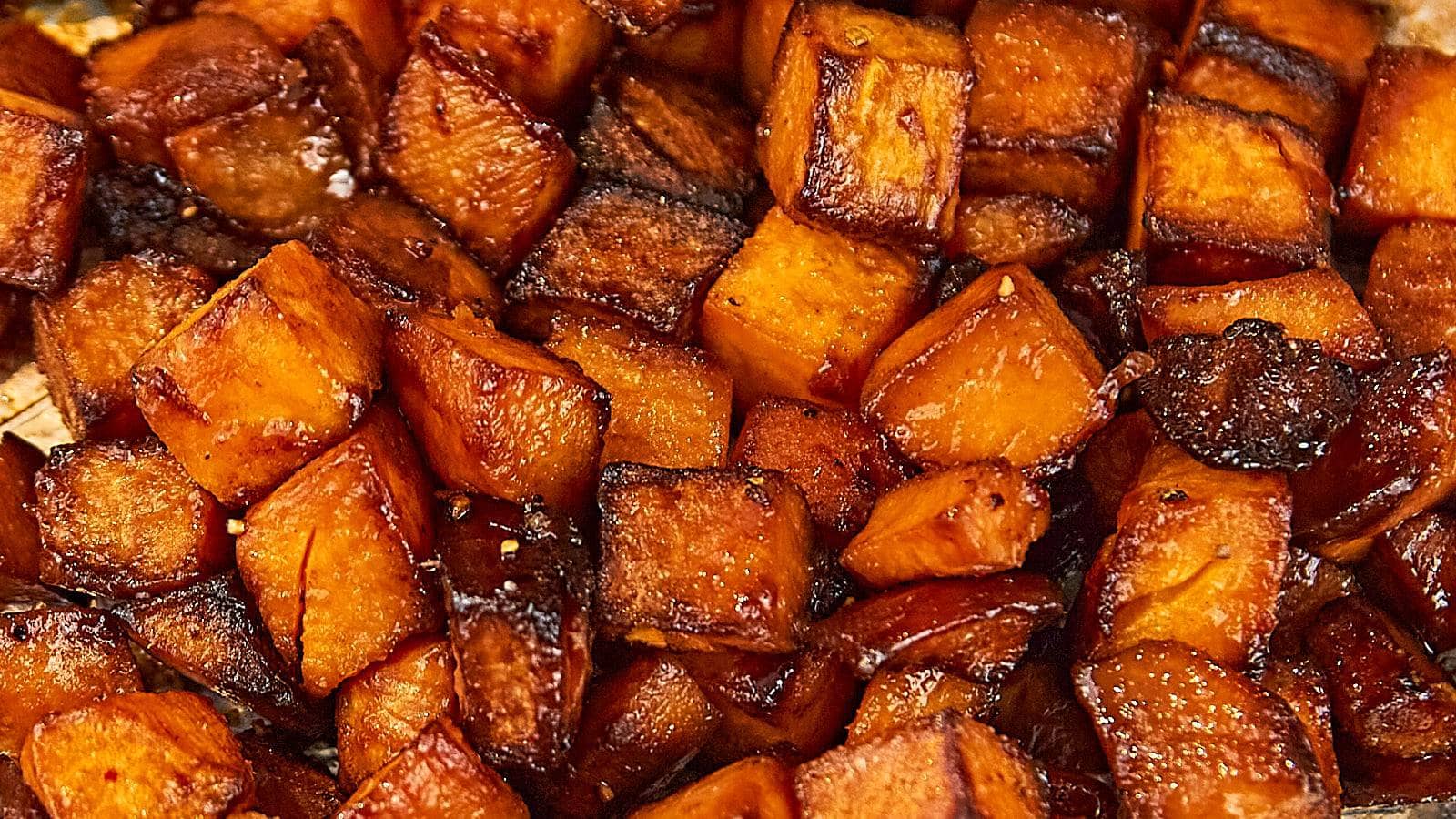 Close-up of roasted sweet potato cubes with a caramelized, golden-brown exterior.