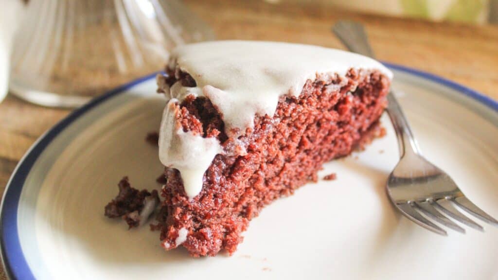 A piece of cake with white frosting on a plate.