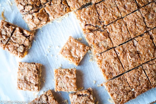Sliced blondie bars are arranged on a sheet of parchment paper, with a few individual bars separated from the main group.