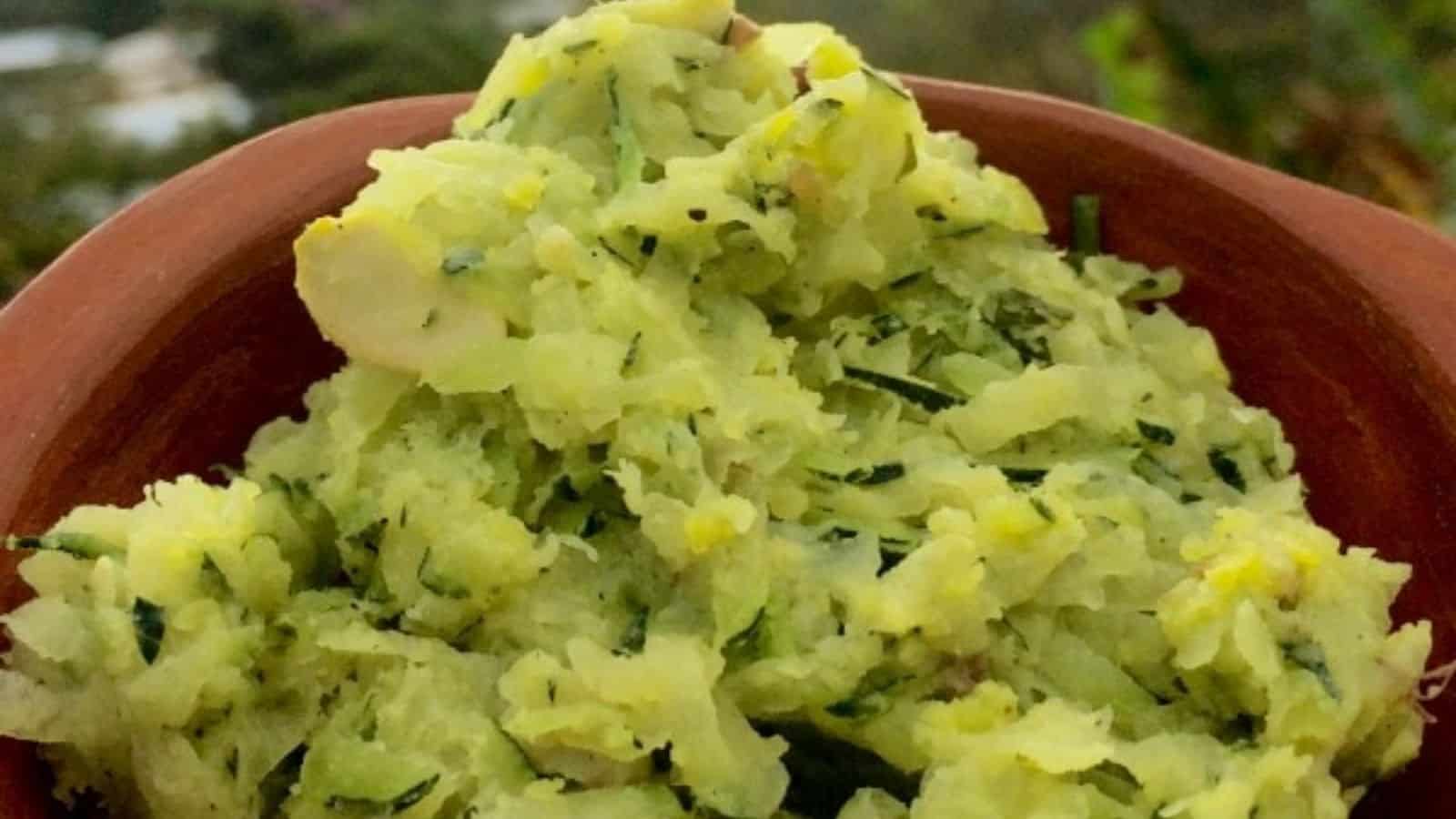 A close-up of a bowl filled with greenish mashed or grated vegetables, possibly containing herbs or spices, placed outdoors.