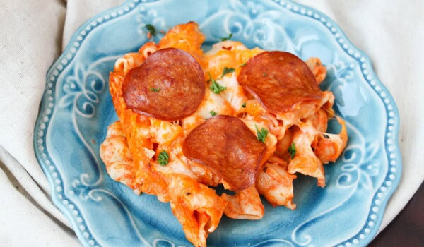 A serving of baked pasta topped with melted cheese, tomato sauce, herbs, and three slices of pepperoni on a blue decorative plate.
