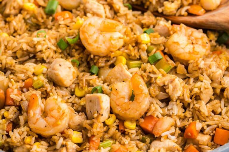 Close-up of shrimp fried rice with diced chicken, carrots, corn, green onions, and rice mixed together.