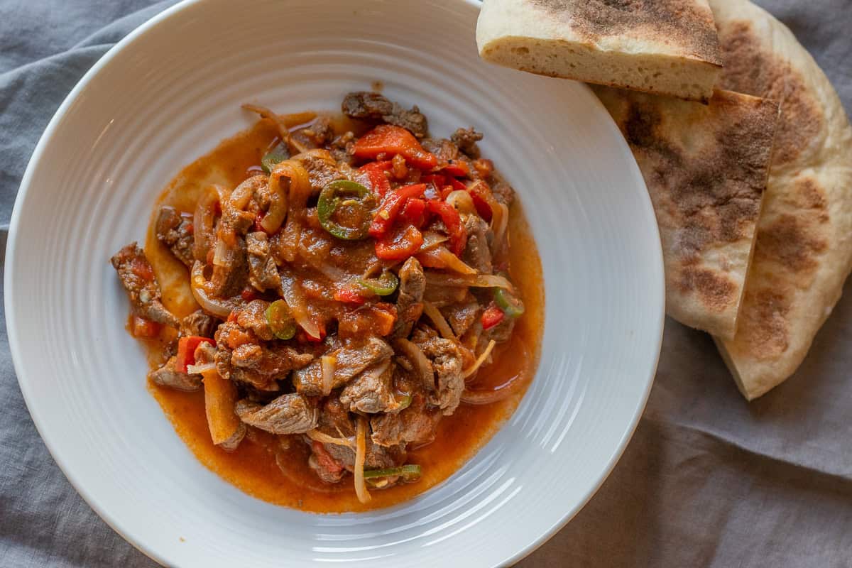A plate of food next to a piece of bread.