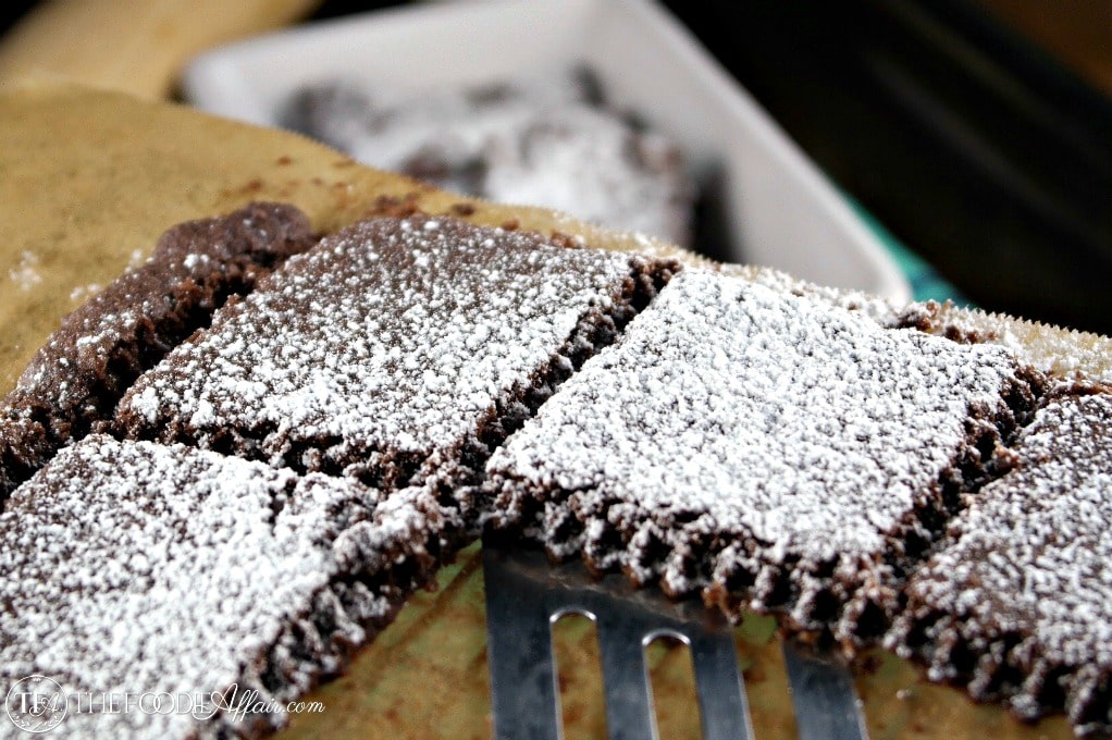 A chocolate brownie with powdered sugar.