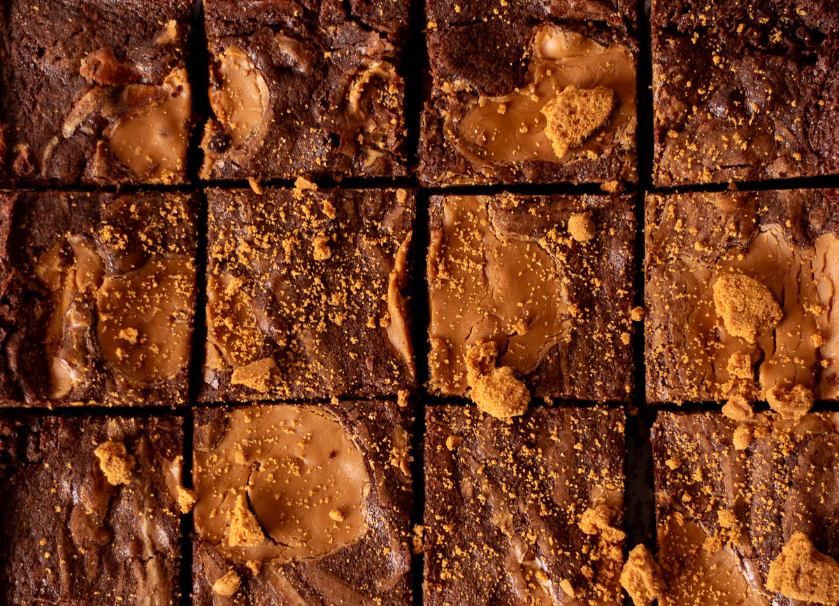 Close-up of sliced brownies topped with swirls of peanut butter and sprinkled with crushed cookie crumbs.