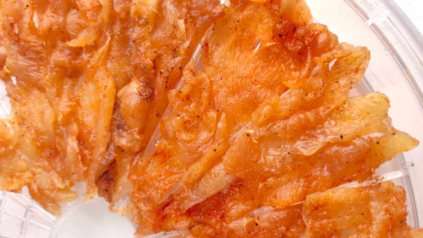 Close-up of orange-colored dried fish fillets with visible seasoning, arranged on a clear plate.