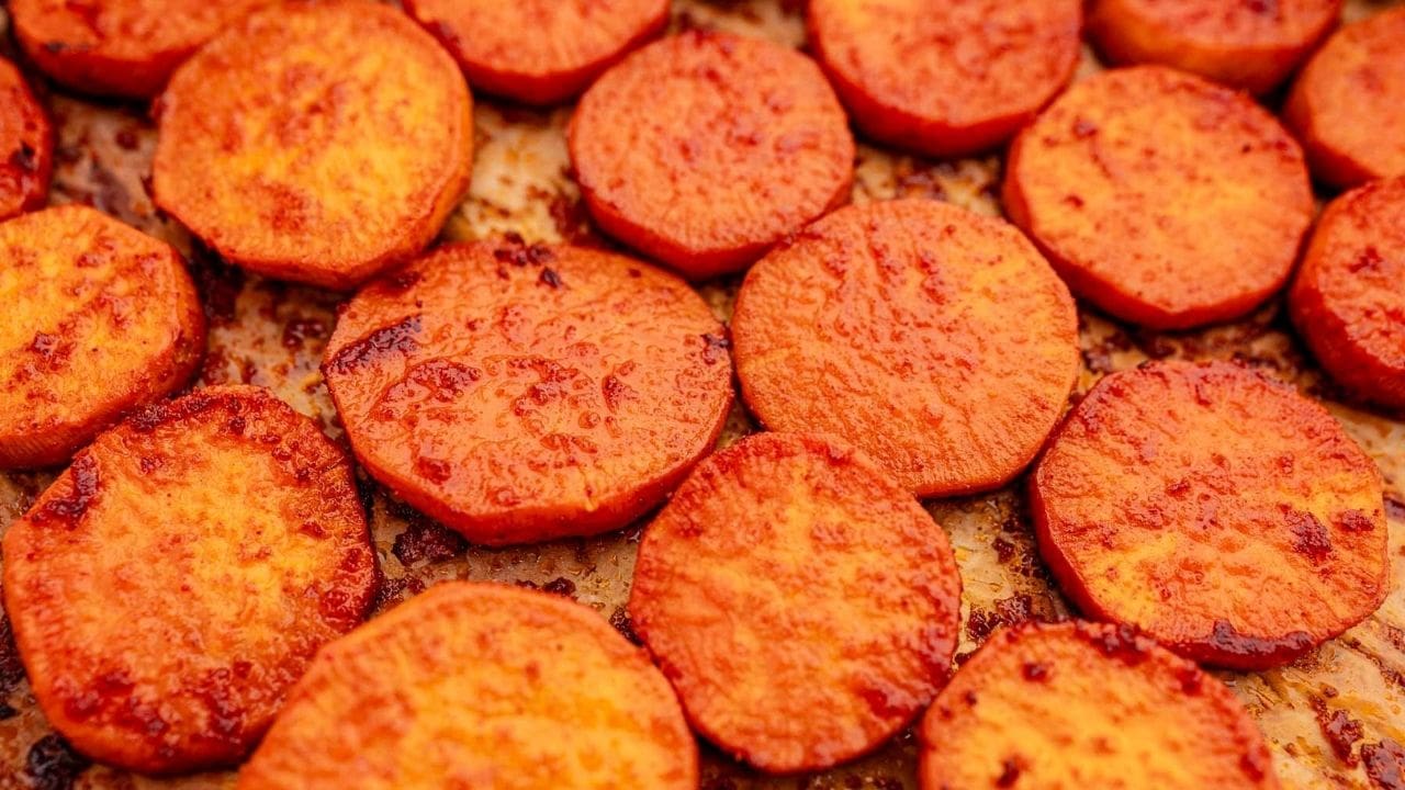 Close-up of baked sweet potato slices arranged on a baking sheet.