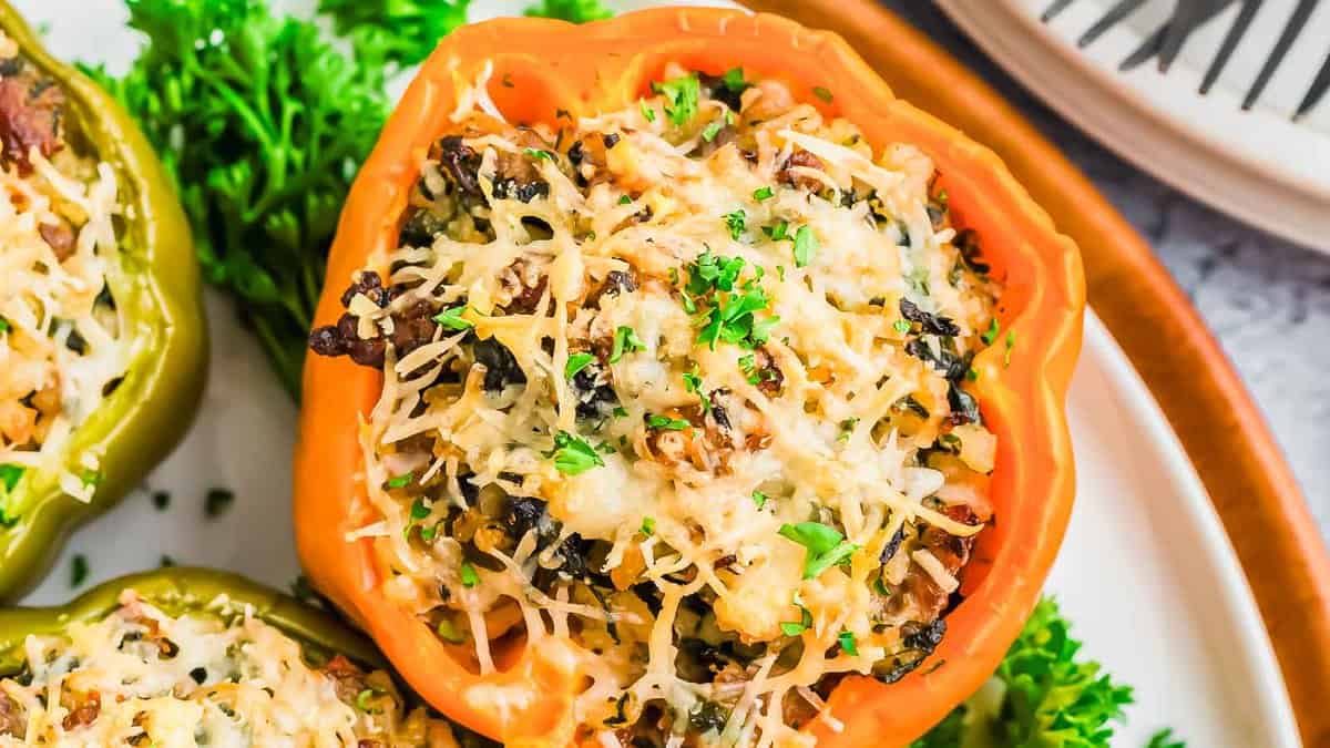 Close-up of a stuffed bell pepper filled with rice, ground meat, vegetables, and topped with melted shredded cheese, garnished with chopped parsley.