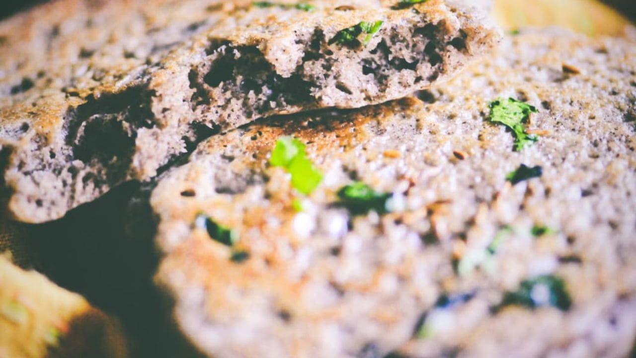 Close-up of two pieces of flatbread with visible green herbs baked into the surface.