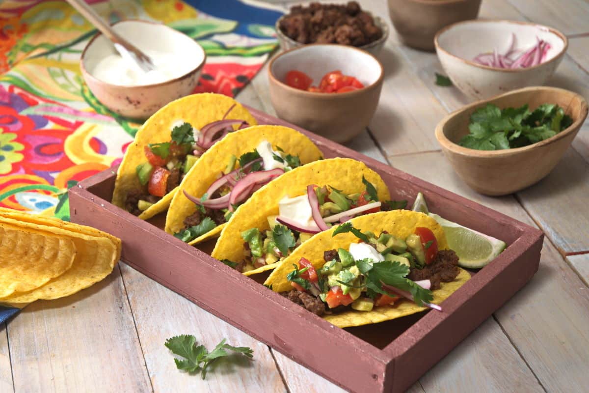 A tray of tacos with various toppings.