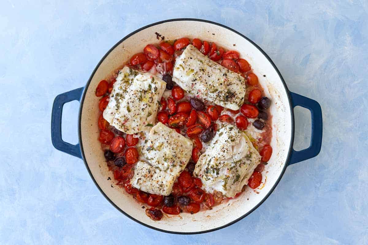 A pan of food with tomatoes and fish.