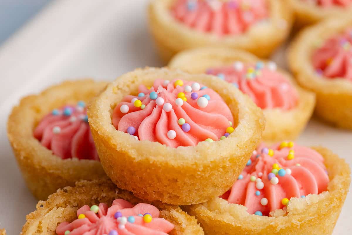 A group of small cookies with pink frosting and sprinkles.