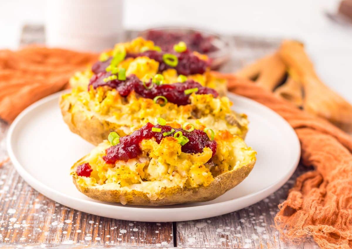 A plate with twice-baked potatoes stuffed with a cheesy filling, topped with cranberry sauce and chopped green onions.