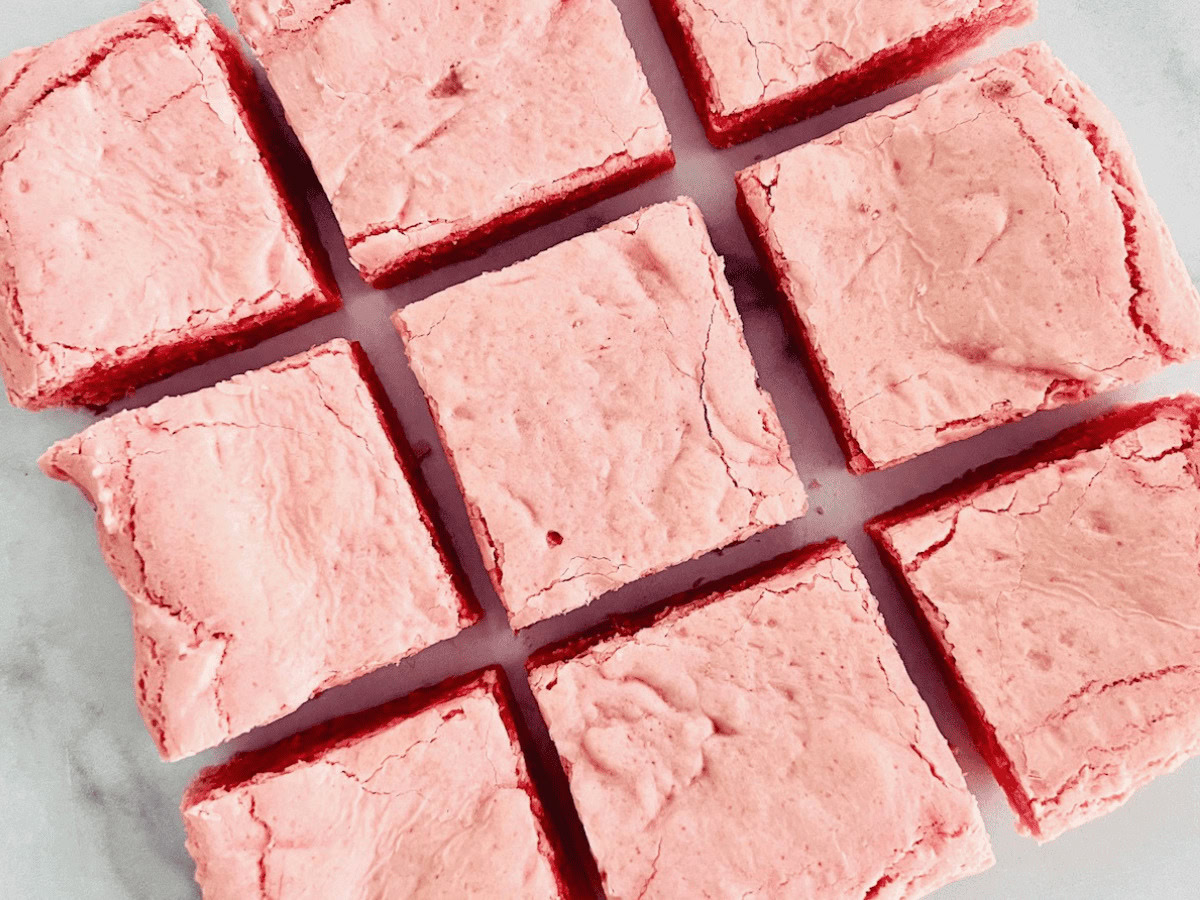 Nine pink frosted dessert bars arranged in a three-by-three grid on a light surface.