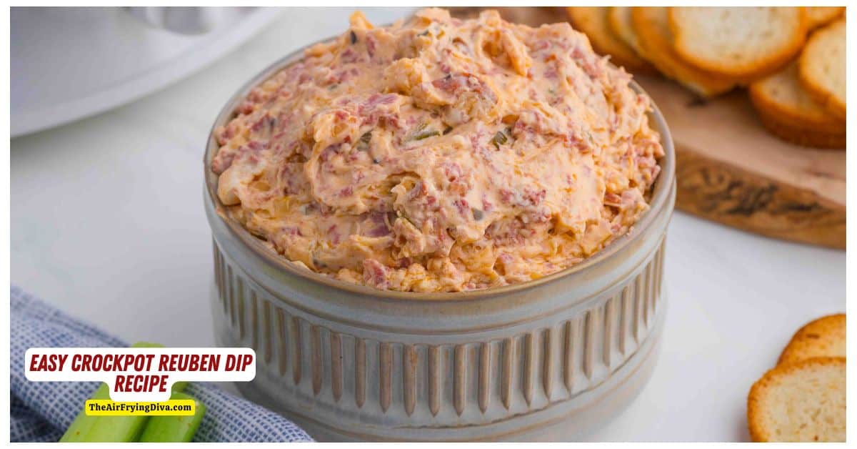 A bowl of creamy Reuben dip with visible pieces of corned beef and cheese, set on a table next to a plate of toasted bread slices.
