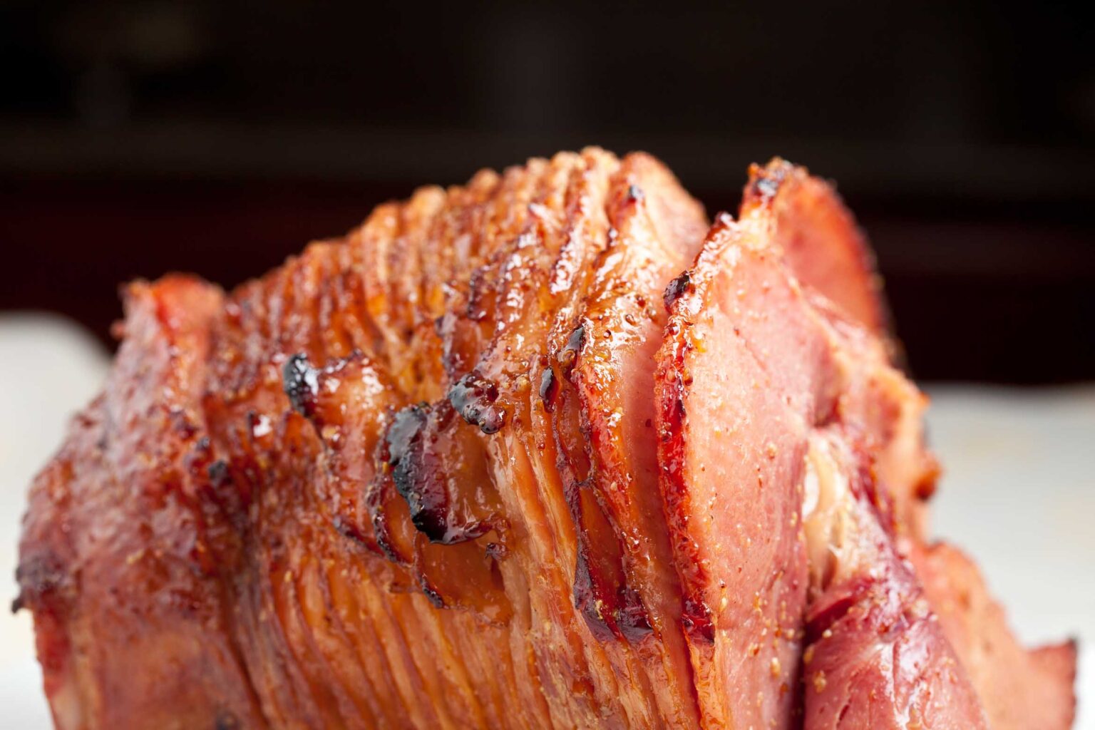 Close-up of a sliced, glazed ham with a browned, caramelized exterior.