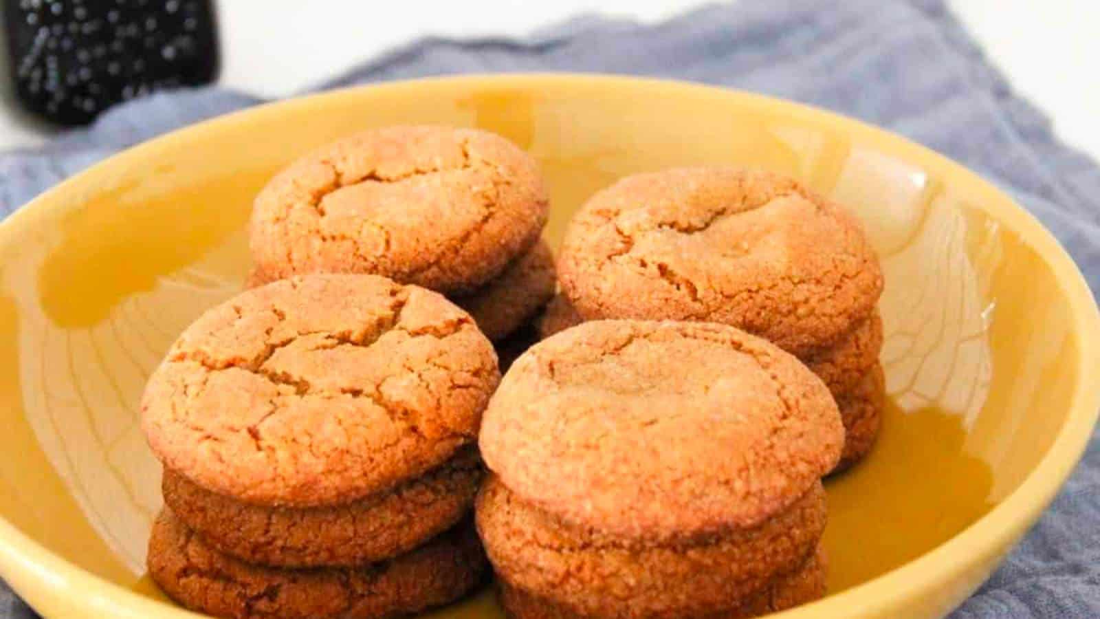 A yellow plate holds two stacks of round, golden-brown cookies on a blue cloth.