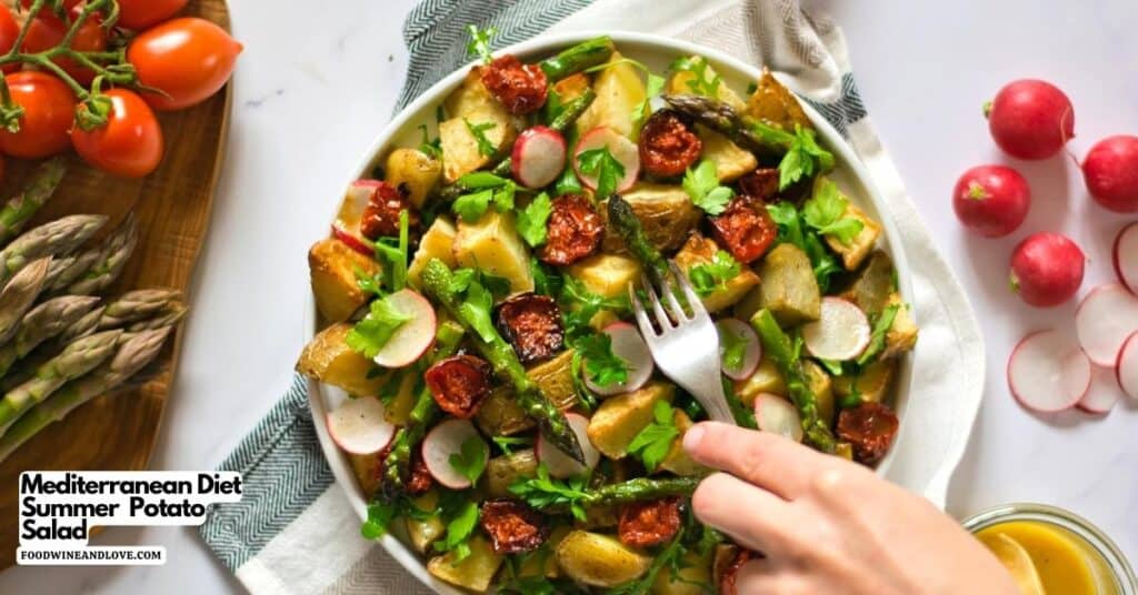 A bowl of Mediterranean potato salad with roasted potatoes, asparagus, radishes, sun-dried tomatoes, and parsley, with a hand holding a fork ready to eat.