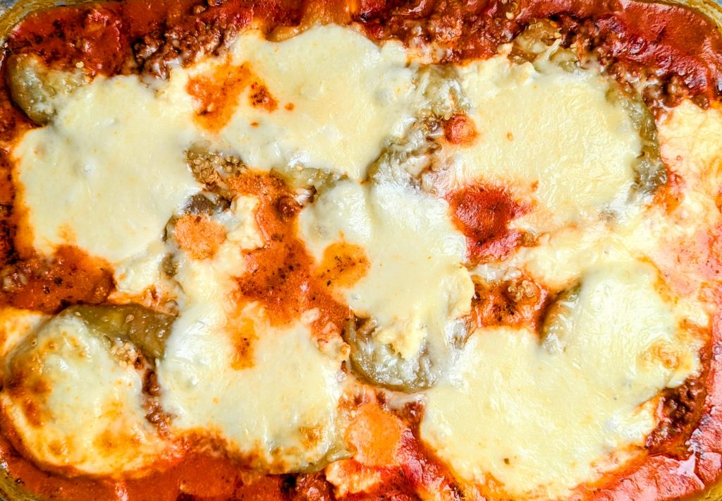 Close-up of a baked lasagna with layers of melted cheese, tomato sauce, and visible meat and pasta.