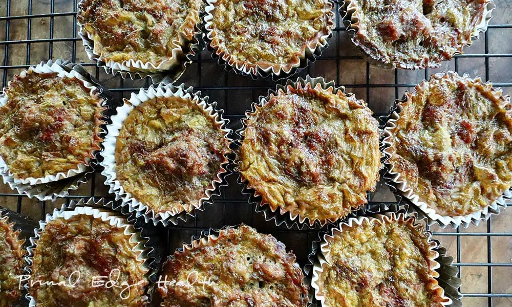Muffins in white paper liners are cooling on a wire rack, with a golden-brown, textured top surface.