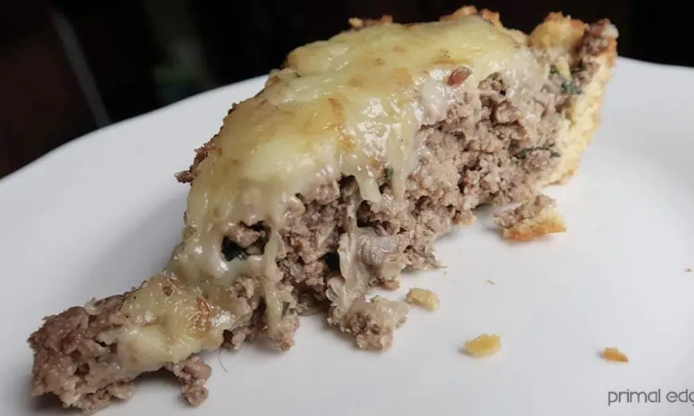 A slice of ground meat pie topped with melted cheese, served on a white plate.