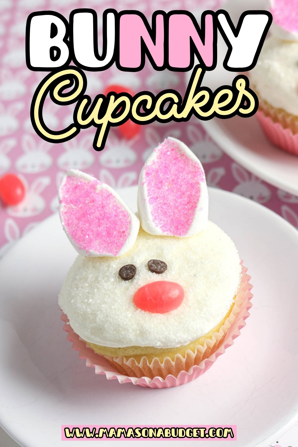 A cupcake decorated to look like a bunny with marshmallow ears, pink sprinkles, candy eyes, and a pink candy nose on a white plate. Text reads Bunny Cupcakes.