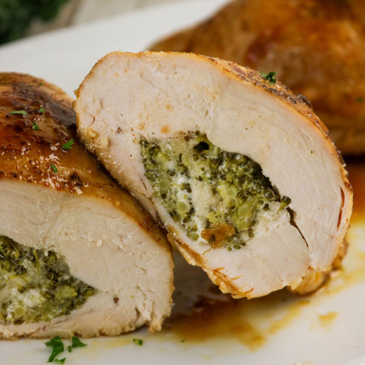 Sliced stuffed chicken breast filled with a broccoli and cheese mixture, served on a white plate with sauce.