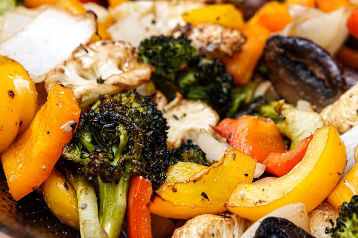 Close-up of assorted roasted vegetables including broccoli, yellow squash, bell peppers, onions, mushrooms, and cauliflower.