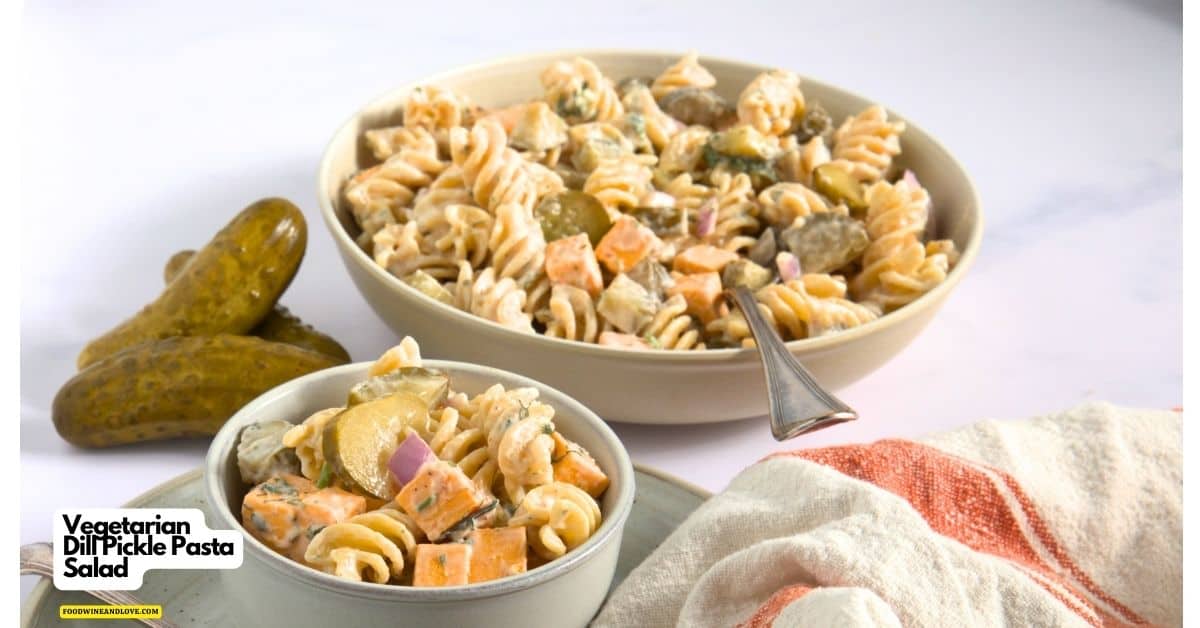 Two bowls of vegetarian dill pickle pasta salad with rotini, pickles, cheese cubes, and red onions, set on a white surface with whole pickles and a striped cloth nearby.