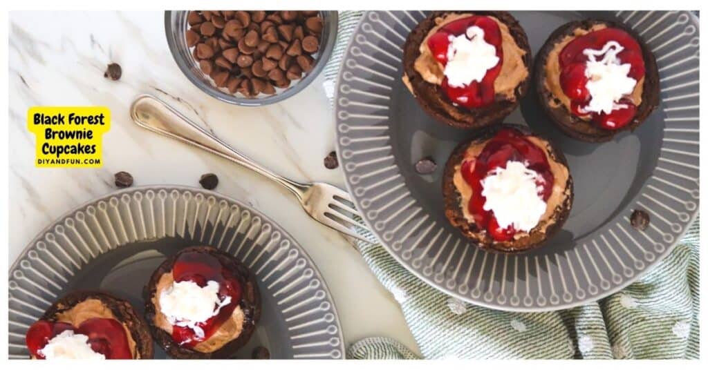 Three brownie cupcakes topped with chocolate cream, cherry sauce, and whipped cream are displayed on plates beside a bowl of chocolate chips and a fork.