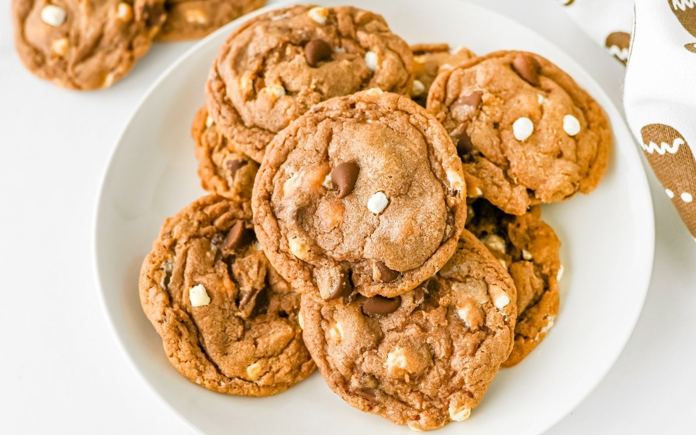 A white plate filled with several chocolate chip cookies made with both white and milk chocolate chips, set on a white surface.