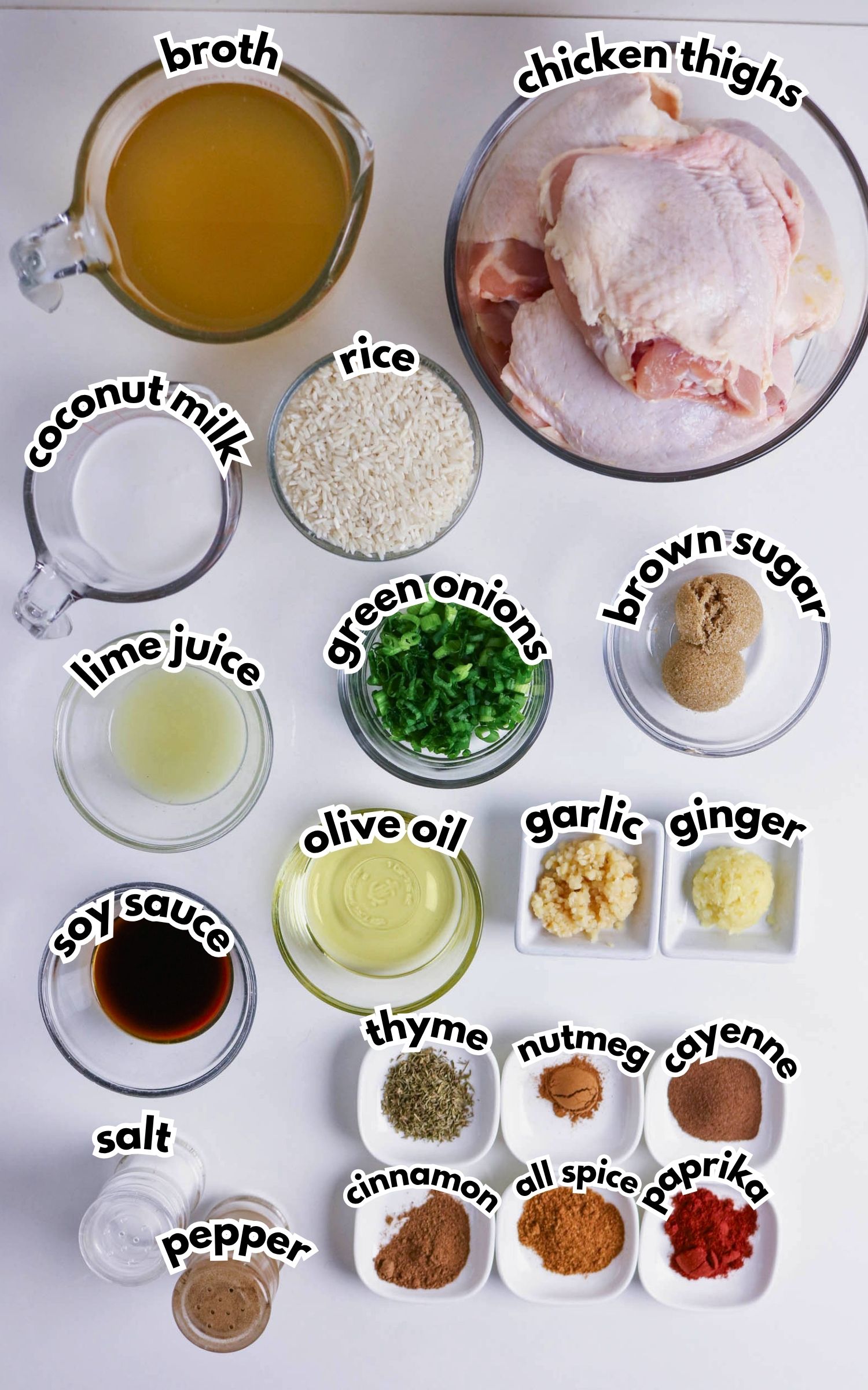 Assorted labeled ingredients including chicken thighs, broth, rice, coconut milk, lime juice, green onions, brown sugar, seasonings, soy sauce, olive oil, garlic, and ginger on a white surface.